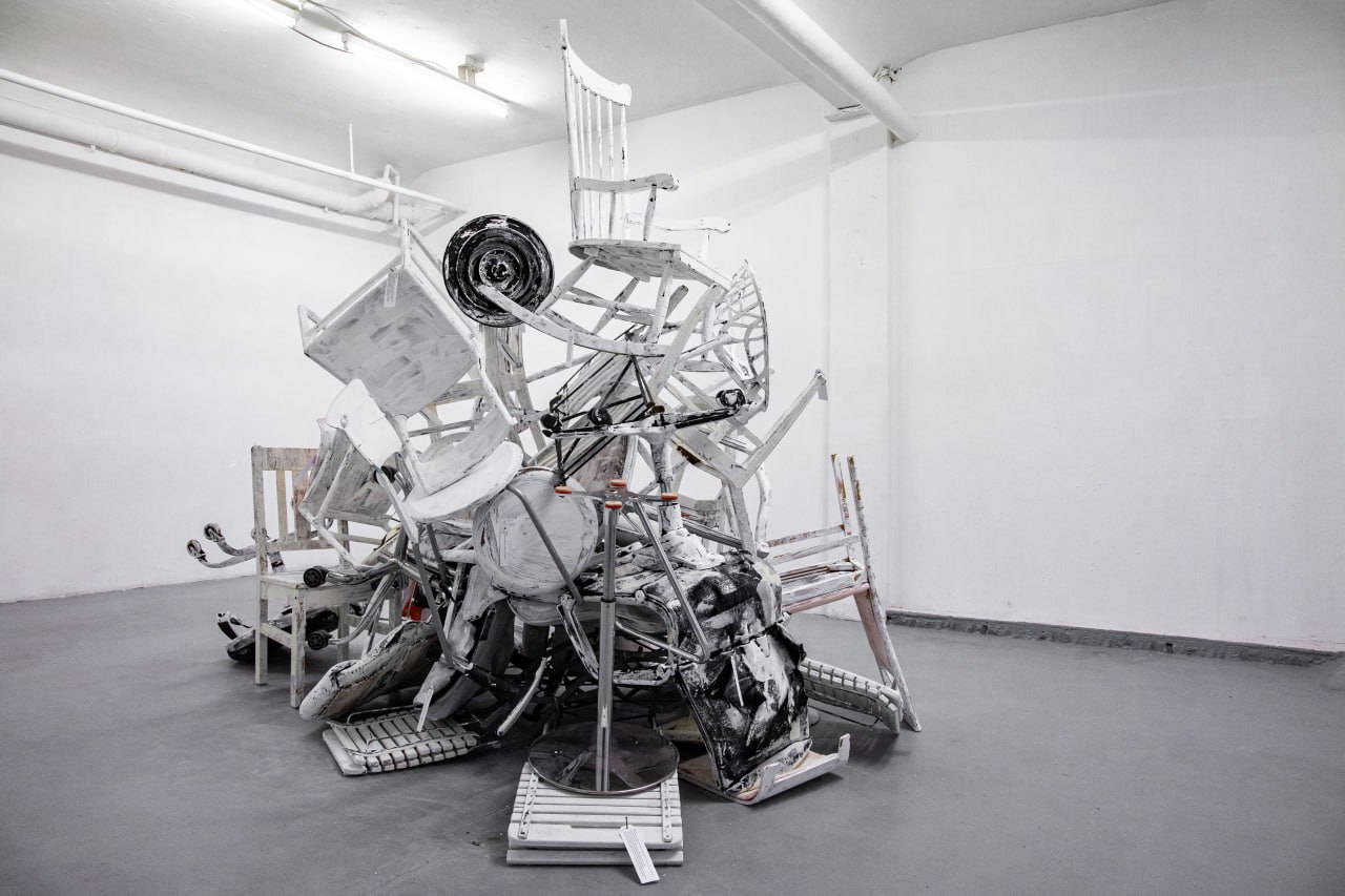 Bild von der Ausstellung: Verschiedene Stühle zu einem Kunstwerk aufgetürmt
